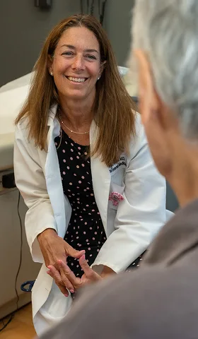 A smiling physician in conversation with a patient