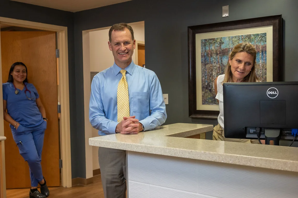 A physician and staff at the front desk of the office